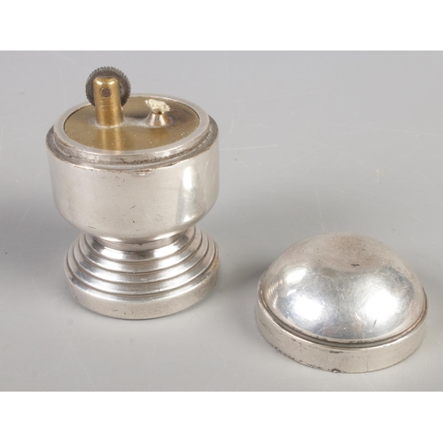 80 - A white metal table lighter raised on circular stepped base. (8cm)