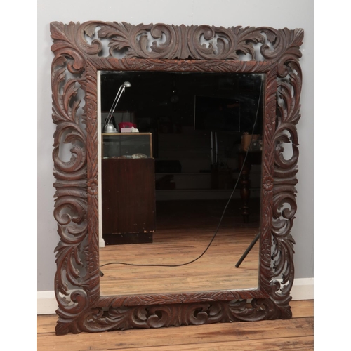 116 - A large French oak mirror with carved and pierced border. 160cm x 95cm.