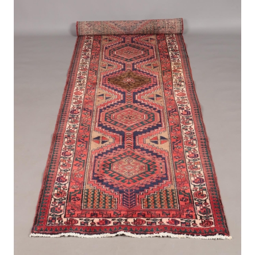 118 - A large red ground thick pile Persian Heriz runner with geometric design. 310cm x 106cm