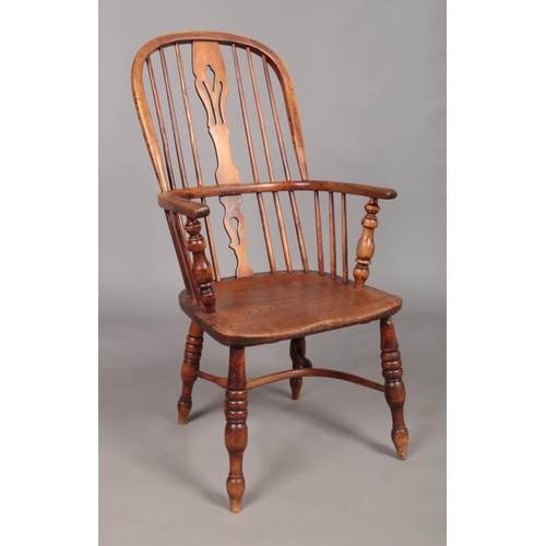 128 - A 19th century ash/elm Windsor arm chair with crinoline stretcher and pierced slat.