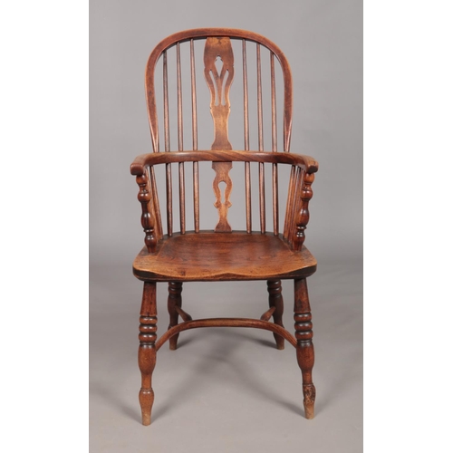 129 - A 19th century ash/elm Windsor arm chair with crinoline stretcher and pierced slat.