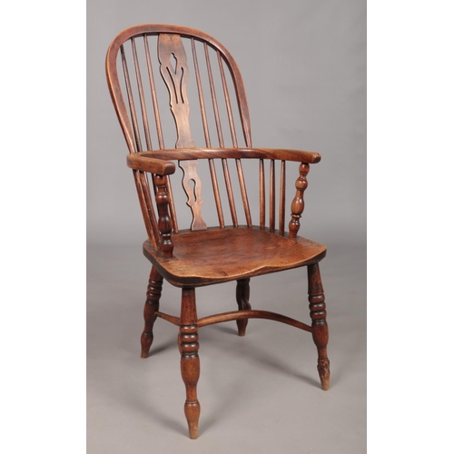 129 - A 19th century ash/elm Windsor arm chair with crinoline stretcher and pierced slat.