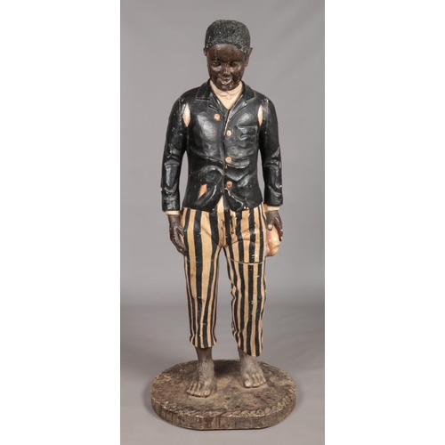 77 - A large carved wooden blackamoor and polychrome statue of a young boy dressed in ragged jacket and s... 