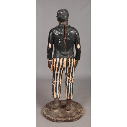 77 - A large carved wooden blackamoor and polychrome statue of a young boy dressed in ragged jacket and s... 