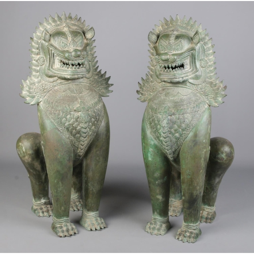 79 - A large pair of bronze Khmer style sculptures modelled as temple lions. Height 60cm.