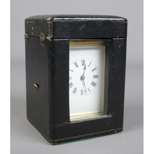 85 - A French brass carriage clock with leather and glass travel case. Having Roman numeral markers and c... 