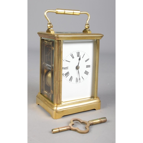 85 - A French brass carriage clock with leather and glass travel case. Having Roman numeral markers and c... 