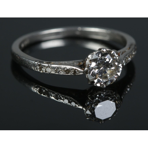 91 - A platinum and diamond ring. The larger stone flanked by diamond set shoulders. Size L 1/2. 2.91g.