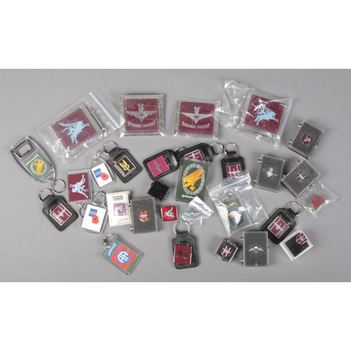 223 - A collection of military car badges, pin badges and keyrings. Mostly Parachute Regiment.