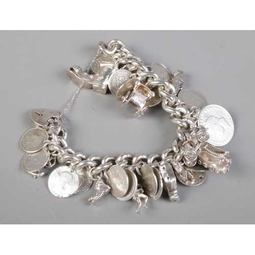 409 - A silver and white metal charm bracelet, with charms including horse's head, boot, cart and three pe... 