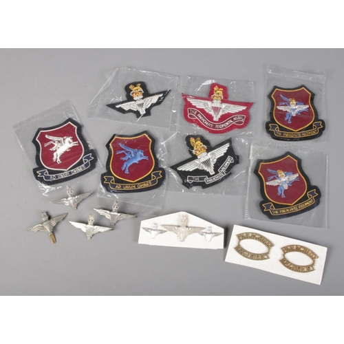 506 - A collection of Parachute Regiment white metal badges and sew on badges.