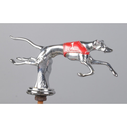 513 - A Desmo car mascot formed as a running Greyhound, with painted red jersey.