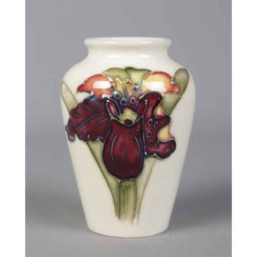 515 - A Moorcroft pottery white ground vase, with Orchid decoration. 9.5cm tall.