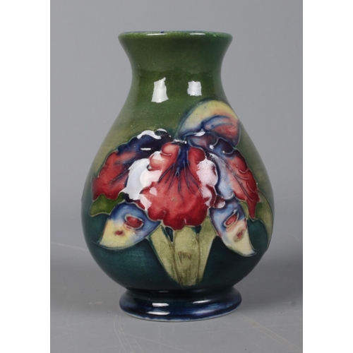 517 - A Moorcroft pottery green ground vase featuring orchid decoration. 9.5cm tall.