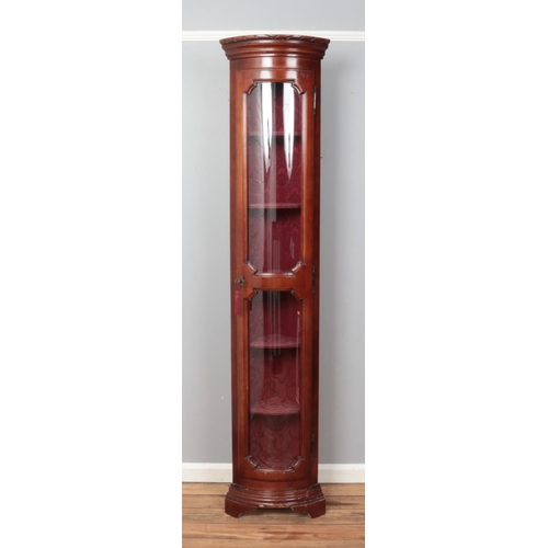 533 - A slender convex mahogany and glass fronted display unit, with key and upholstered interior. 204cm t... 