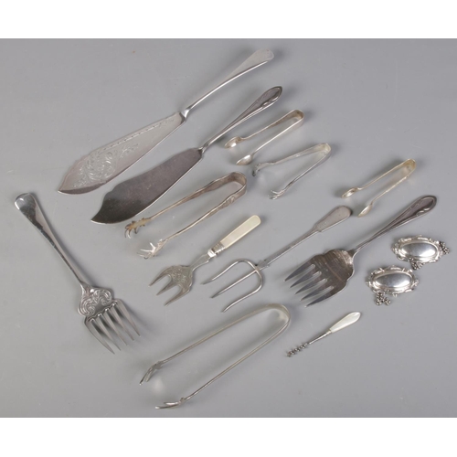 228 - A quantity of mostly silver plated flatware. Including fish knives, sugar tongs, mother of pearl han... 