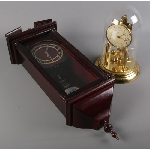 266 - One Hess torsion clock along with a mahogany wall clock. Torsion clock with plastic dome.