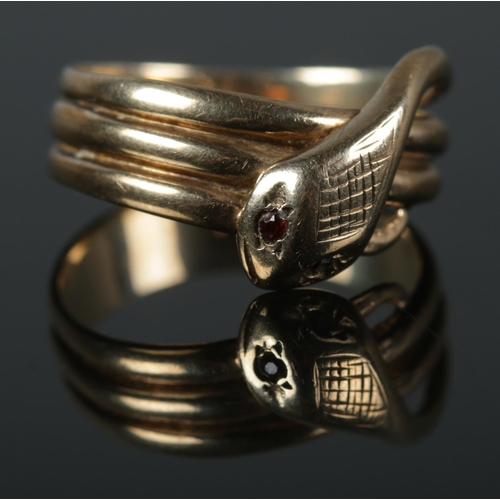 385 - A 9ct coiled snake ring featuring garnet set eyes and cross hatch detail to head. Size R 4.67g.