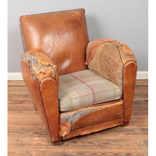 546 - A tan leather fireside armchair with wool tartan cushion.