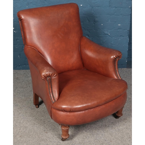 624 - A studded tanned faux leather armchair.