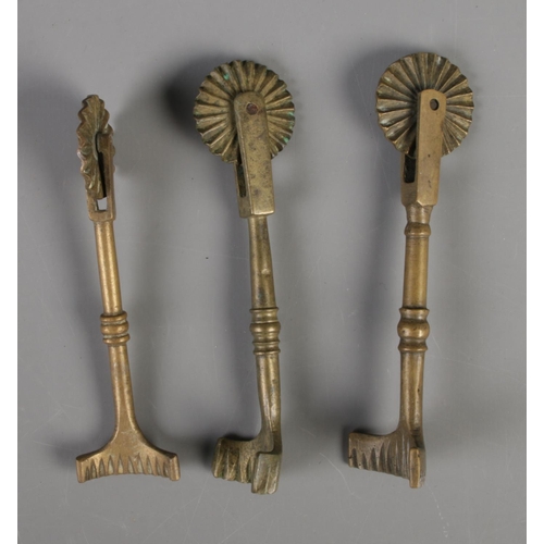 132 - Three brass pastry jiggers each featuring singular wheel, knopped stem and arched cutter.