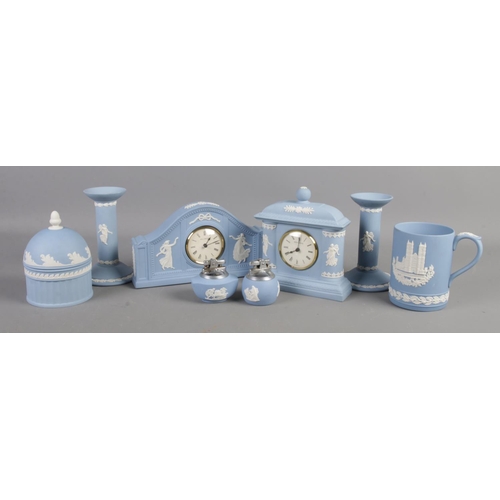 156 - A collection of Wedgwood jasperware. Includes two clocks, pair of candlesticks, lighters etc.