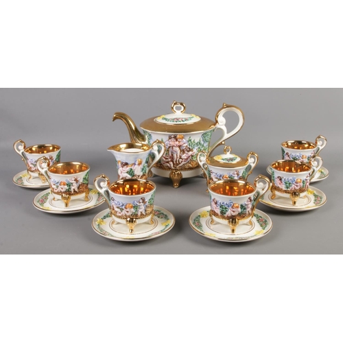 160 - A Capodimonte six place tea set, with gilt edging and decorated with cherubs. Comprising of cups, sa... 