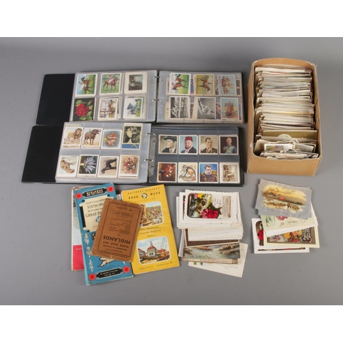 17 - A large quantity of vintage postcards along with two albums of cigarette cards.