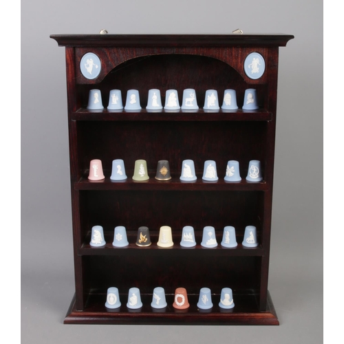 76 - A Wedgwood thimble display stand containing thirty-one Wedgwood thimbles, many Christmas examples.