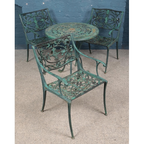 586 - A painted cast iron pierced tavern table and three chairs.