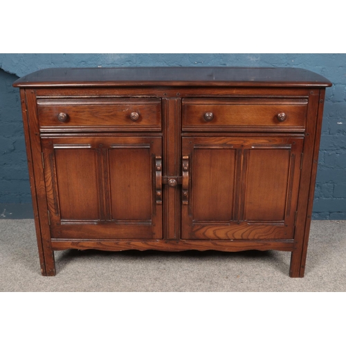 591 - An Ercol dark Old Colonial sideboard, with two drawers over panelled doors.