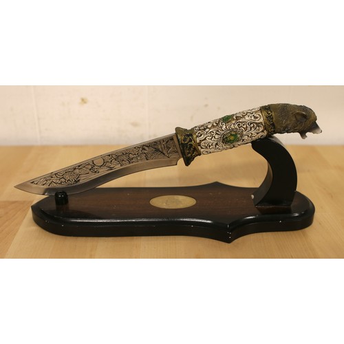 88 - A hunting knife featuring etched and carved Wolf decoration with stand.