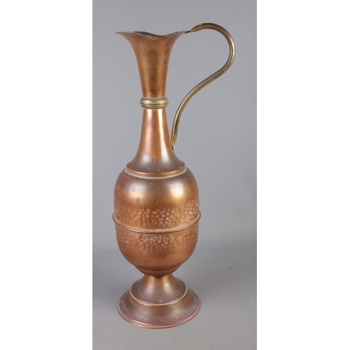 92 - A tall copper water jug featuring hammered detailing.