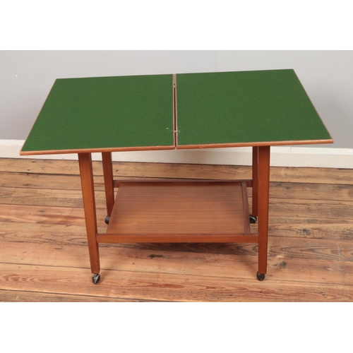 439 - A modern fold-over card table featuring under tier and castors.