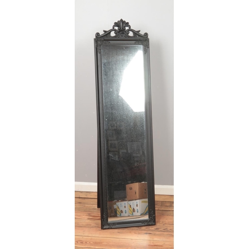 443 - A modern black floor standing mirror featuring carved detail.