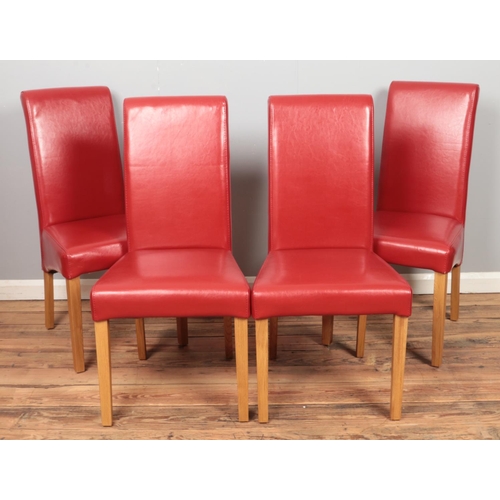 438 - Four red faux leather dining chairs.