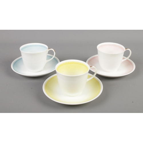 140 - Three Susie Cooper bone china cups and saucers in blue pink and yellow.