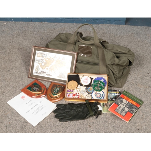 219 - A canvas bag with contents of military ephemera and collectables. Includes badges, compacts, gloves,... 