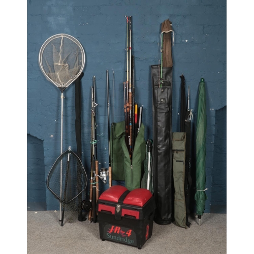 284 - A large quantity of fishing equipment. Includes rods, nets, umbrella, tackle box, Daiwa fishing rod,... 