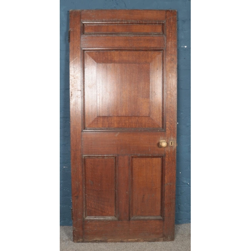 299 - A large panelled oak door, with brass handle and key. Height: 204cm, Width: 90cm.