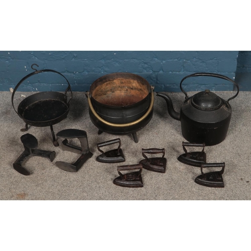 306 - A collection of metal wares to include cast iron pan, irons and cauldron.