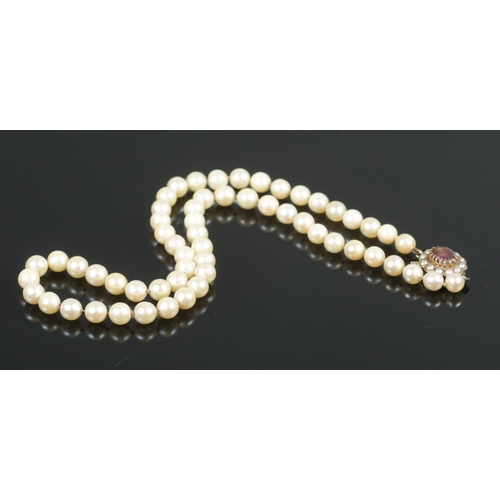 357 - A cultured pearl necklace, with 9ct Gold clasp and central amethyst coloured stone.