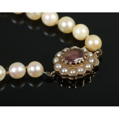 357 - A cultured pearl necklace, with 9ct Gold clasp and central amethyst coloured stone.