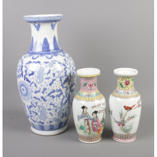 70 - Large oriental style blue and white vase along with two smaller famille rose vases decorated with bi... 