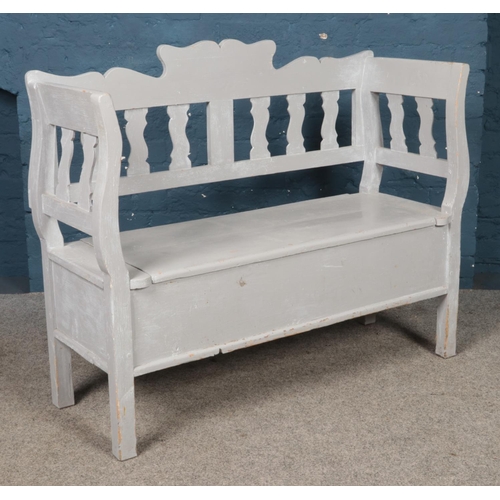 454 - A painted pine monks bench, with lift up storage seat. Height: 95cm, Width: 121cm, Depth: 44cm.