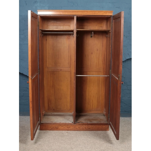 460 - An oak double wardrobe, with arched panels and clover detailing. Height: 182cm, Width: 112cm, Depth:... 