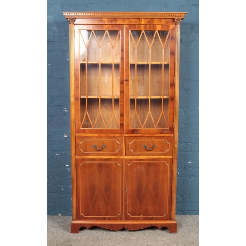 461 - A yew wood bookcase, with astragal glazed front, reeded columns and carved corner sections.  Height:... 