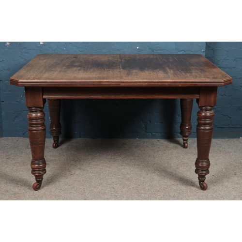 463 - An oak wind out dining table, with turned supports, raised on casters. Height: 74cm, Width: 129cm, D... 