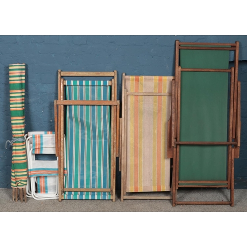 493 - Three vintage folding deck chairs along with a wind blocking screen and folding child's chairs.