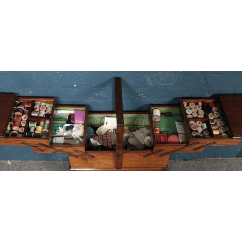 494 - An oak cantilever sewing box with contents.